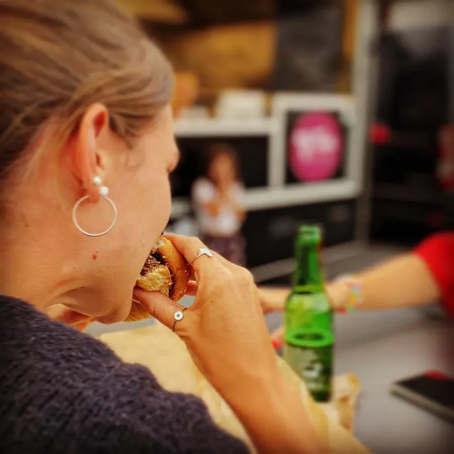 Femme de dos croquant dans un burger